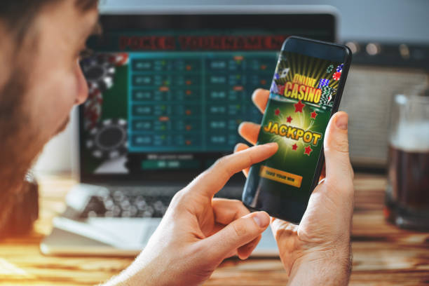 A man holds a smartphone playing a colorful online casino and winning jackpot