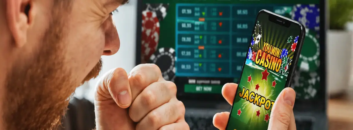 A person excitedly looks at a smartphone playing an online casino