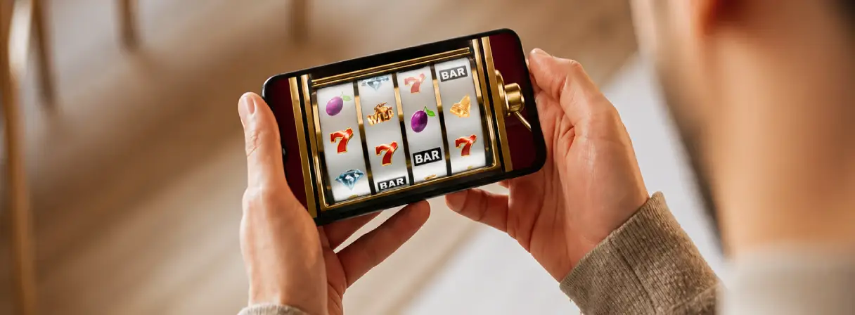 A person holds a smartphone playing an online slot machine game